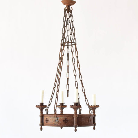 Rusty antique French chandelier with quatrefoil cut outs piercing central ring that holds four torch arms